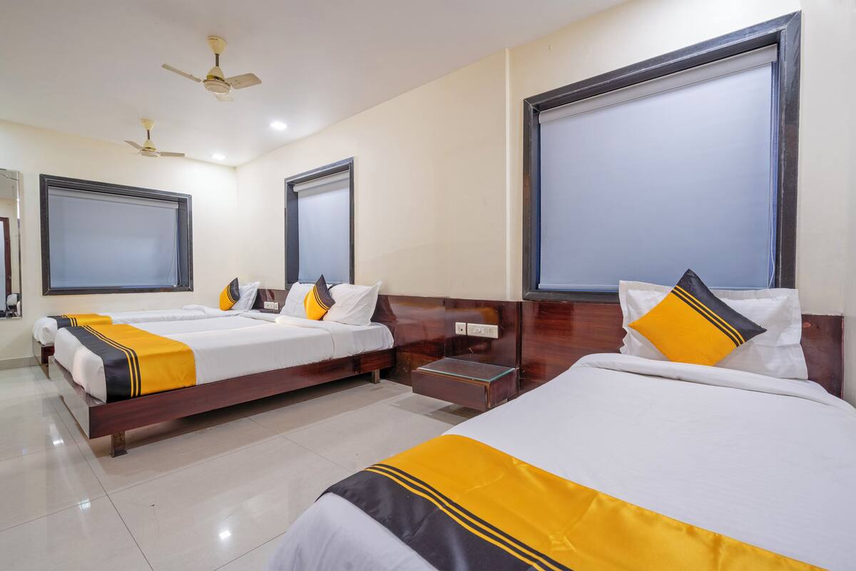 A hotel room with two beds, a wooden headboard, a ceiling fan, and a large window.