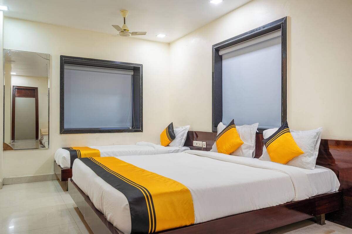 A hotel room with two beds, a large mirror, and a ceiling fan.