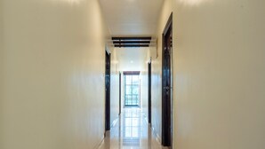 A long, narrow hallway with a tiled floor and a door at the end. - Itsy Hotels M (Vijayawada)