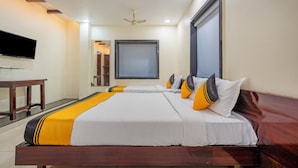 A hotel room with two beds, a flat-screen TV, a ceiling fan, and a large window. - Itsy Hotels M (Vijayawada)