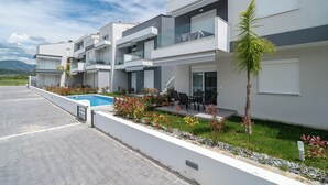 A modern residential building with a swimming pool, outdoor seating, and a well-maintained garden.