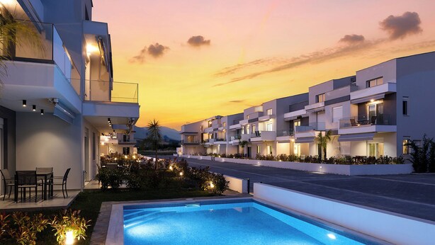 A modern hotel with a swimming pool, multiple balconies, and a sunset view.