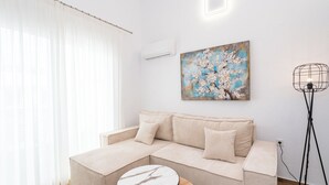 Ein modernes Wohnzimmer mit einer Couch, einem runden Couchtisch, einem Gemälde und einer Stehlampe.
