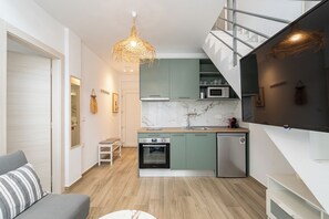 Une cuisine moderne équipée d’un four encastré, d’un four à micro-ondes et d’un lave-vaisselle. Un escalier mène à l’étage supérieur.