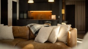 Un salon moderne avec un canapé en cuir, des coussins à motifs et des luminaires suspendus.