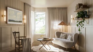 Un salon confortable avec un canapé, un fauteuil, une table et une fenêtre avec des rideaux.