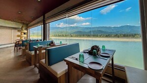 Een restaurant met uitzicht op een rivier en bergen.
