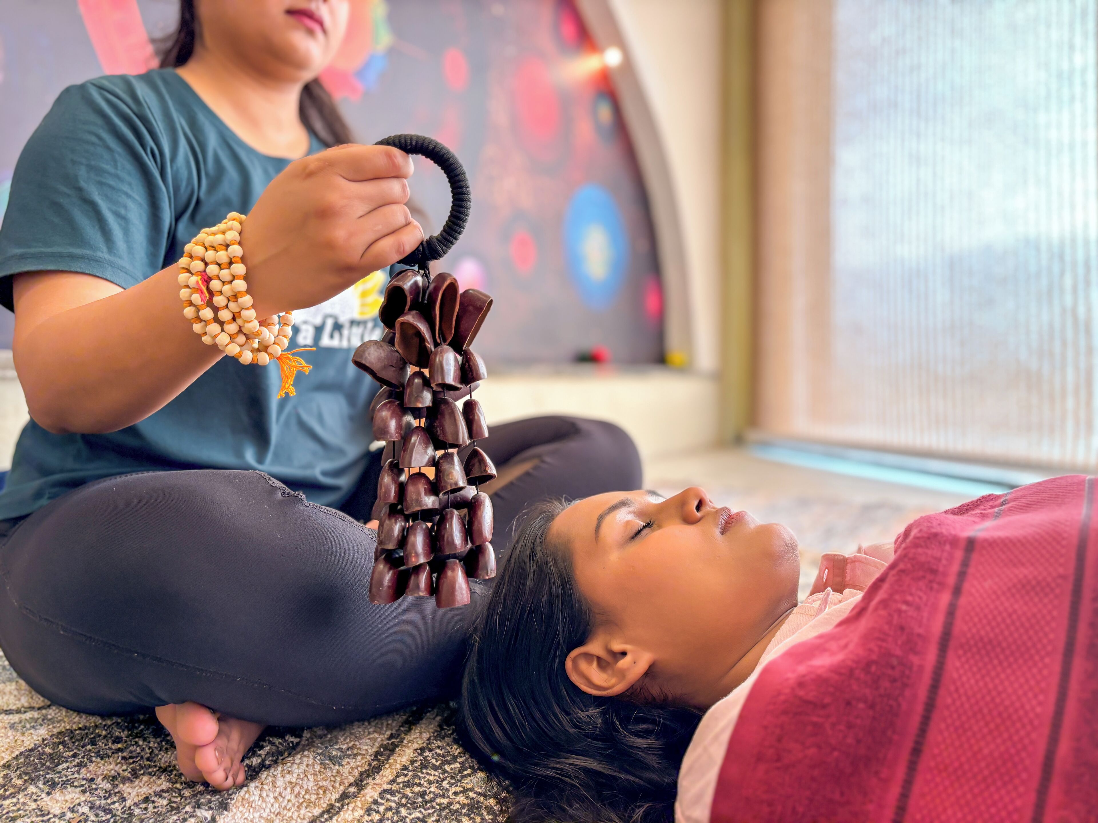 A person sitting on a patterned carpet, holding a black object.