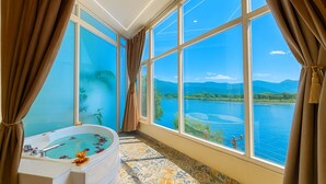 A bathroom with a large bathtub, a view of a lake, and patterned floor tiles. - The Neeraj Ganga Rajmahal Wellness Dream (Rishikesh)