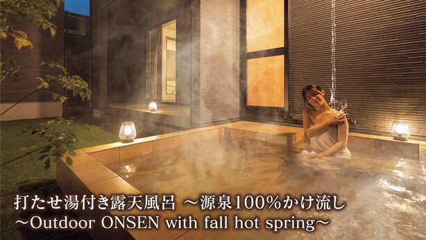 Eine Person entspannt sich in einem Thermalbad im Freien, im Hintergrund ein modernes Gebäude.