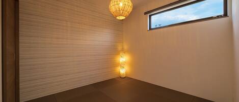 A minimalist room with a large window, a hanging light fixture, and a textured wall.