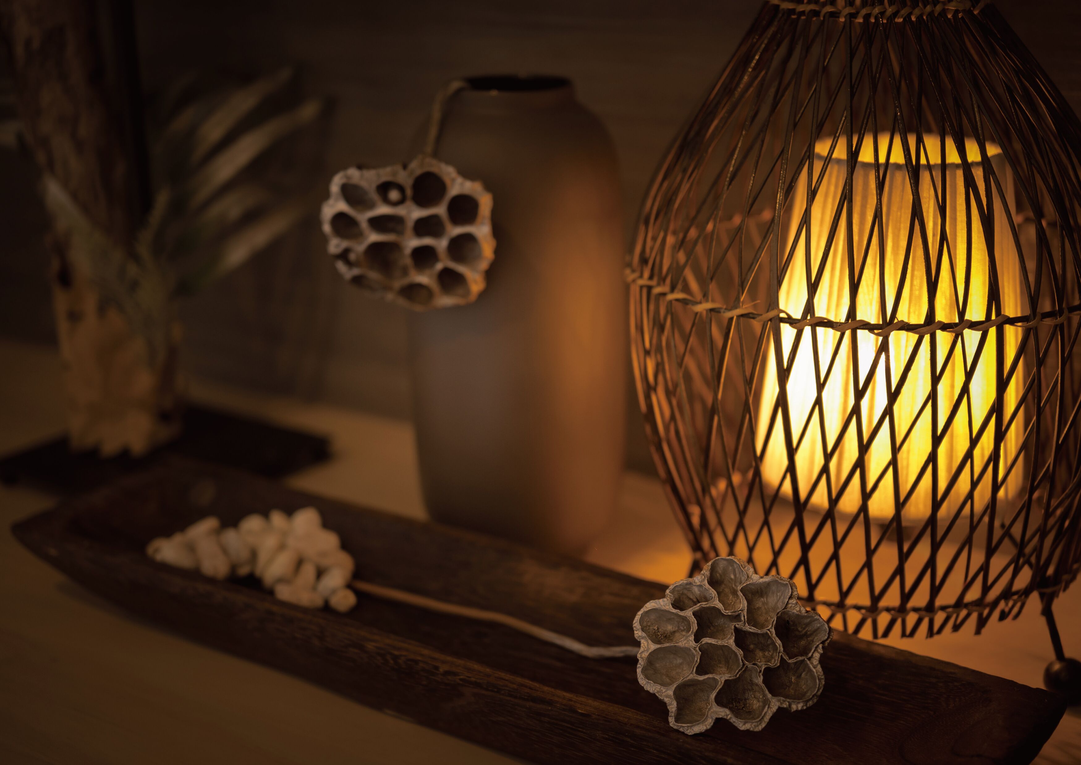 A decorative lamp with a wireframe design, a ceramic vase, and a wooden tray with decorative items.
