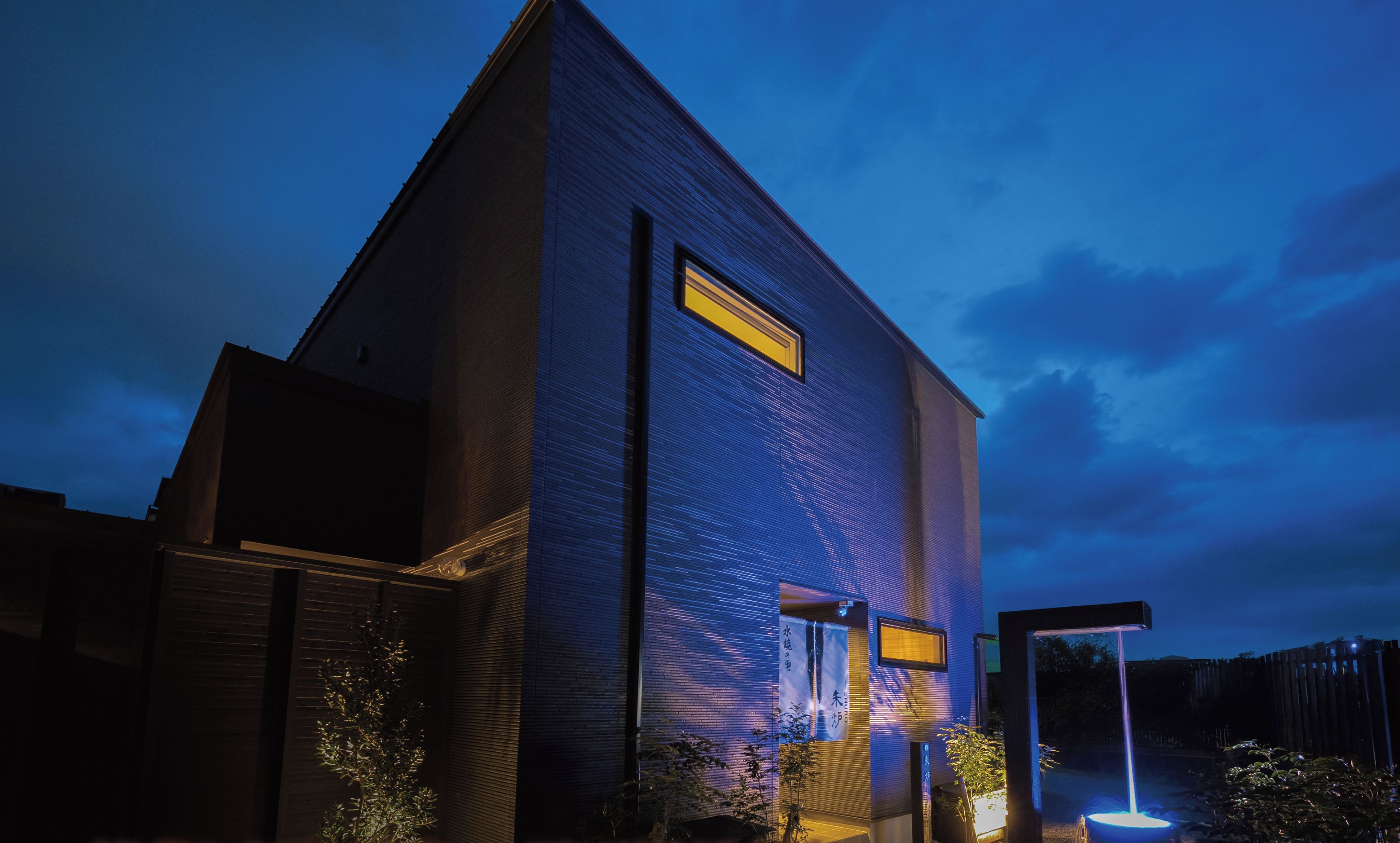 A modern villa with a large window, a door, and a small garden area with a fountain.