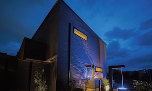 A modern villa with a large window, a door, and a small garden area with a fountain. - Villa suikyo no shizuku (Beppu)