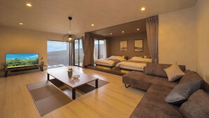 Ein modernes Hotelzimmer mit einem großen Bett, einer Couch, einem Fernseher und einem Essbereich.