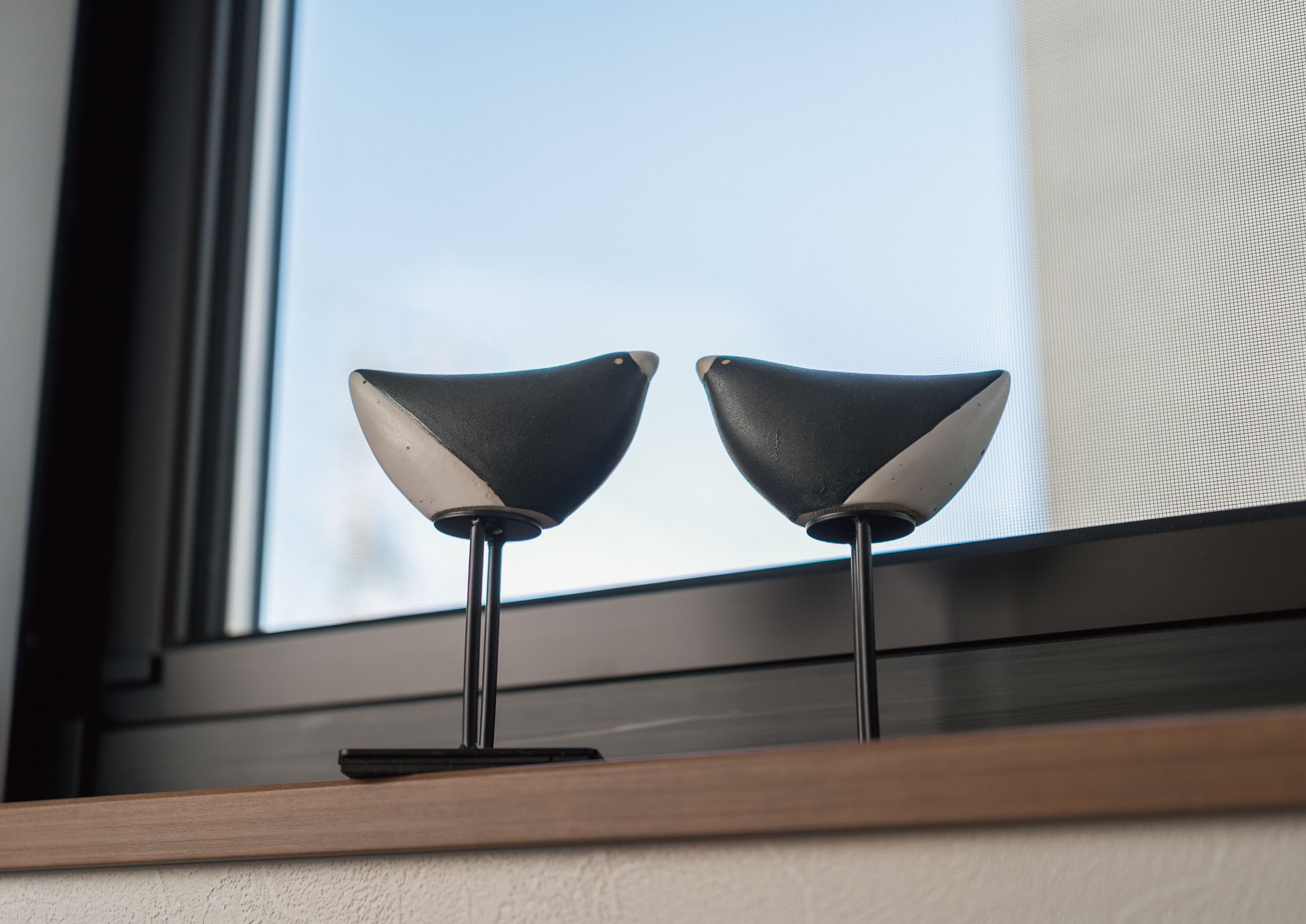 Dos lámparas de pie modernas en blanco y negro sobre un estante de madera cerca de una ventana.