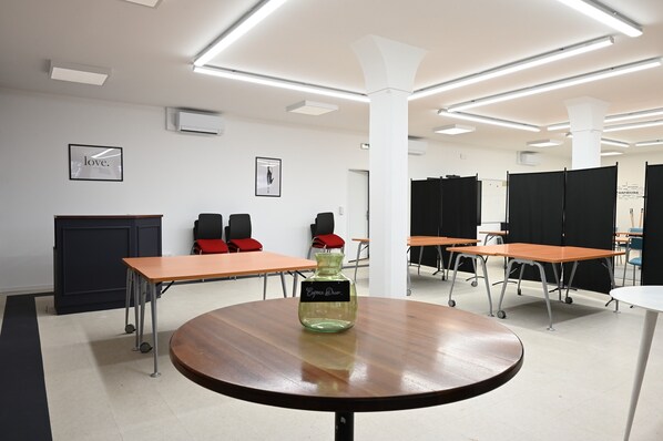 A conference room with tables, chairs, and a central table with a decorative vase.