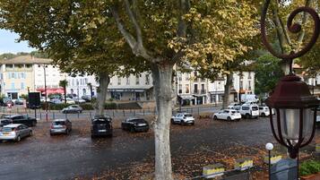 A street view with parked cars, trees, and buildings.