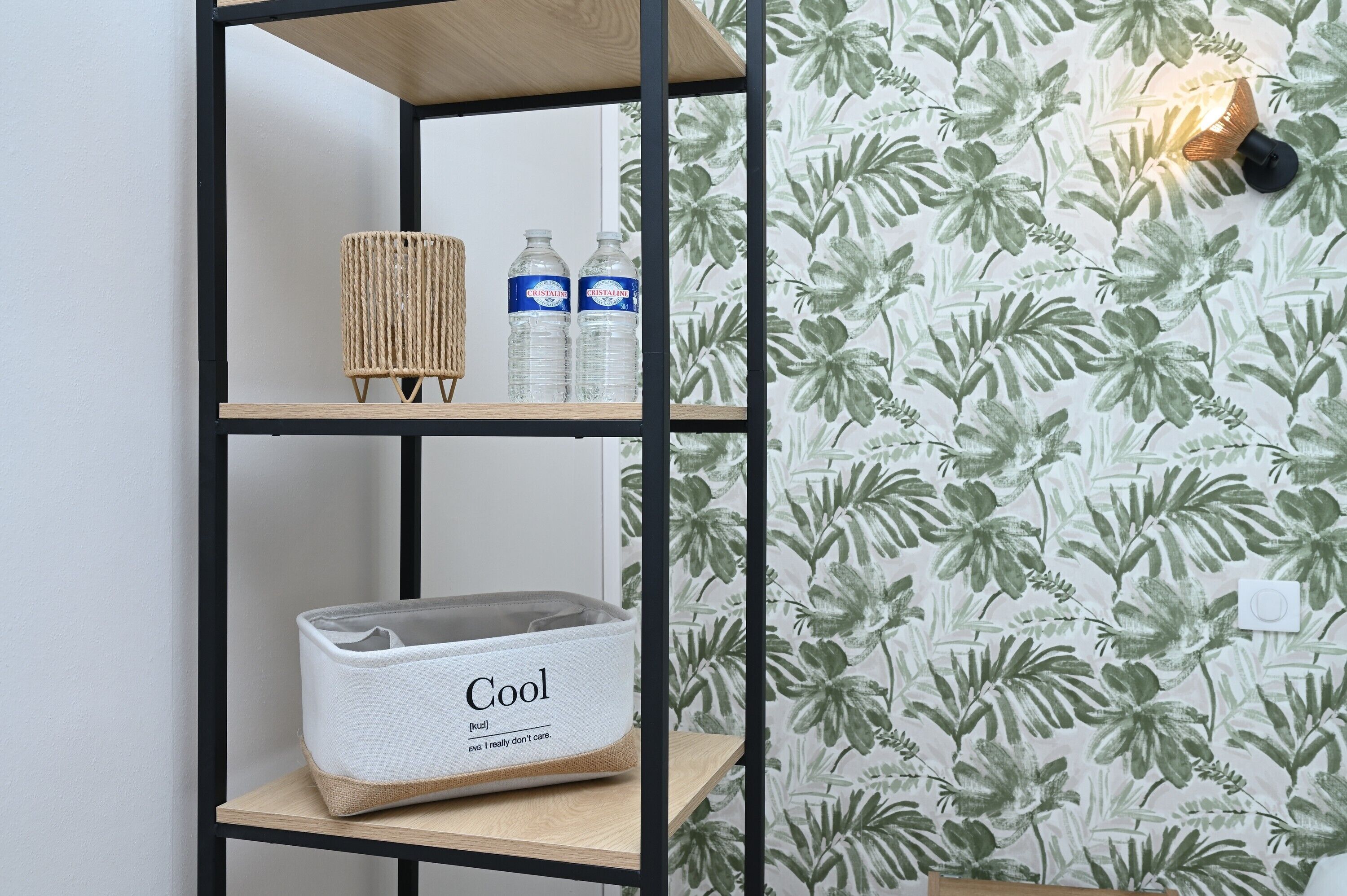 Uma prateleira com uma cesta trançada, duas garrafas de água e uma caixa de armazenamento branca com a etiqueta 'Cool'.