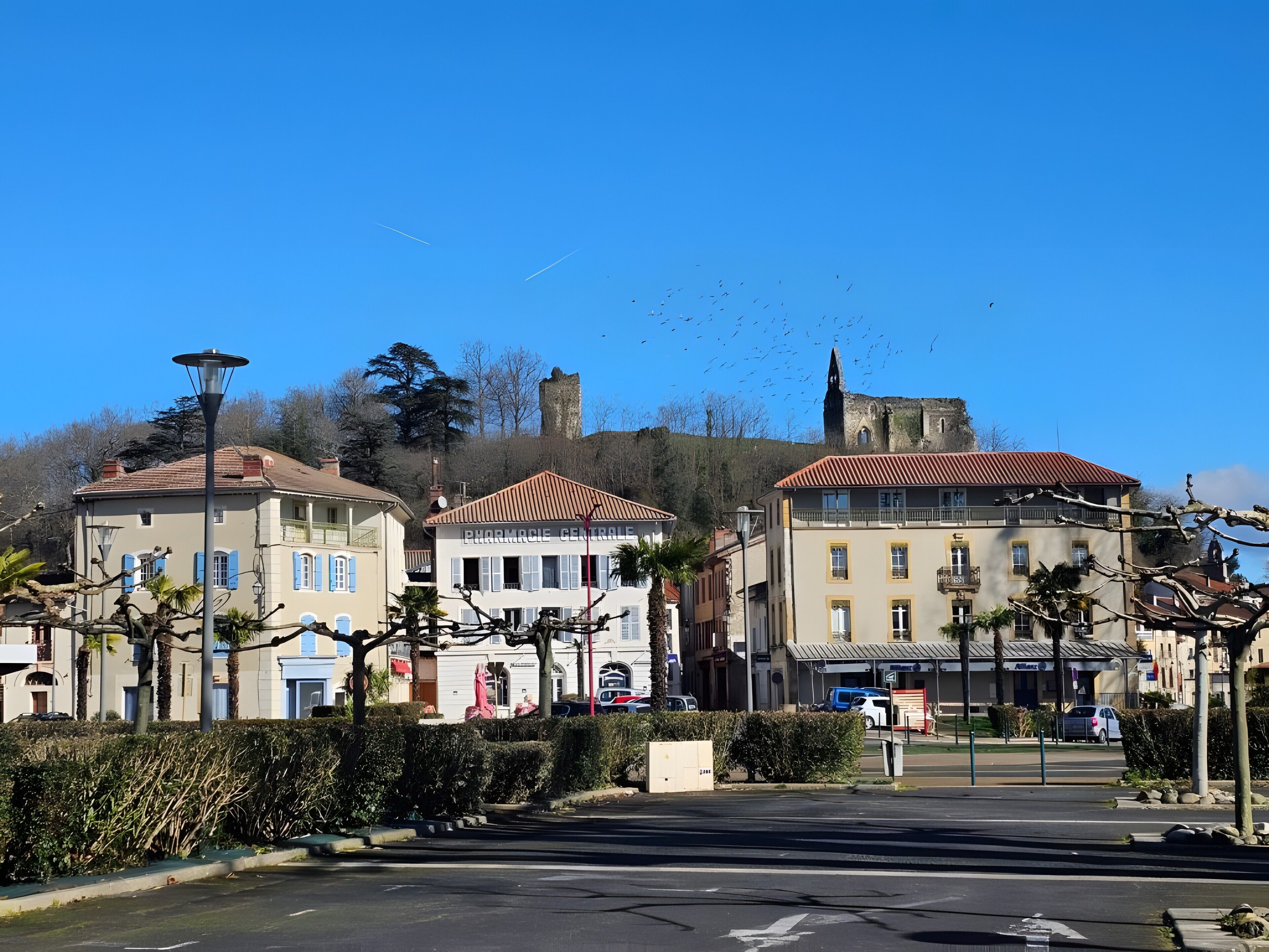 Une vue de rue avec des bâtiments, un ciel dégagé et une tour au loin.