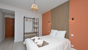 Une chambre à coucher comprenant un lit, un luminaire suspendu, une armoire et une étagère fixée au mur.