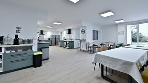 Une cuisine moderne dotée d’un coin repas, d’un espace dédié à la préparation du café et d’une grande fenêtre laissant entrer la lumière naturelle.