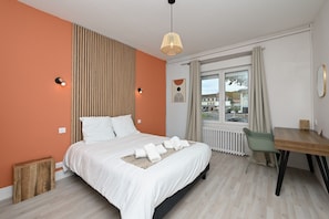 A bedroom with a bed, bedside lamps, a window with curtains, a radiator, a wooden side table, and a chair. - Room 'Double Room' with Shared Terrace, Wi-Fi and Air Conditioning (Salies-du-Salat)