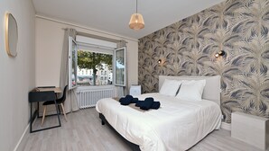 Een slaapkamer met een bed, bureau, stoel, raam en radiator.