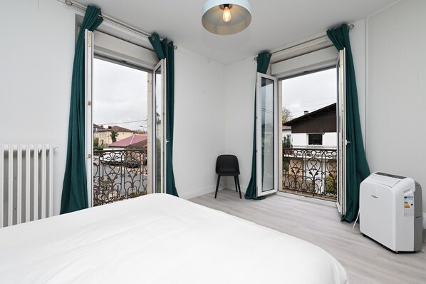 A bedroom with a bed, a chair, a radiator, and a heater.