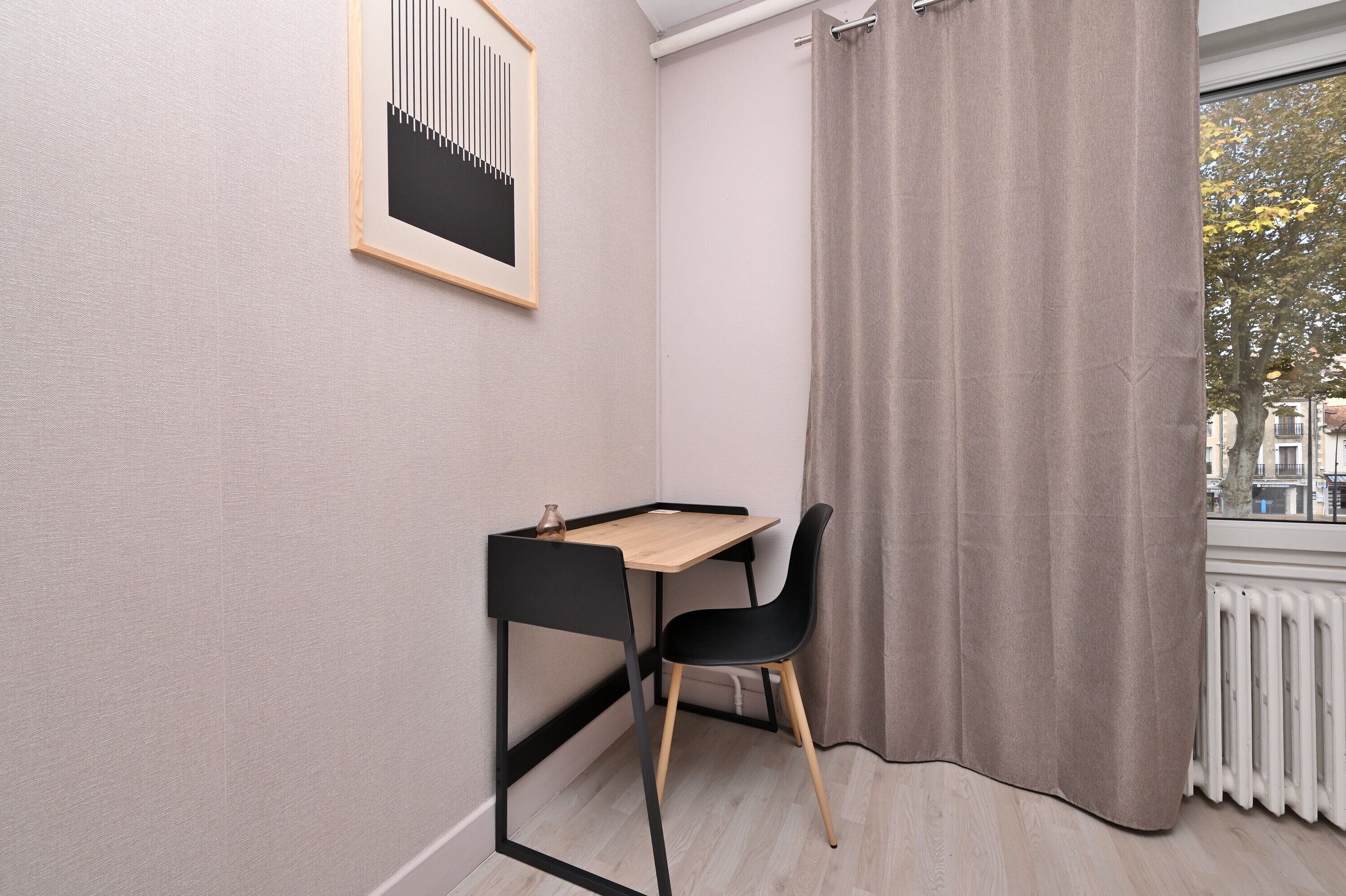 Een hoekappartement met een bureau, stoel en een raam met gordijnen.