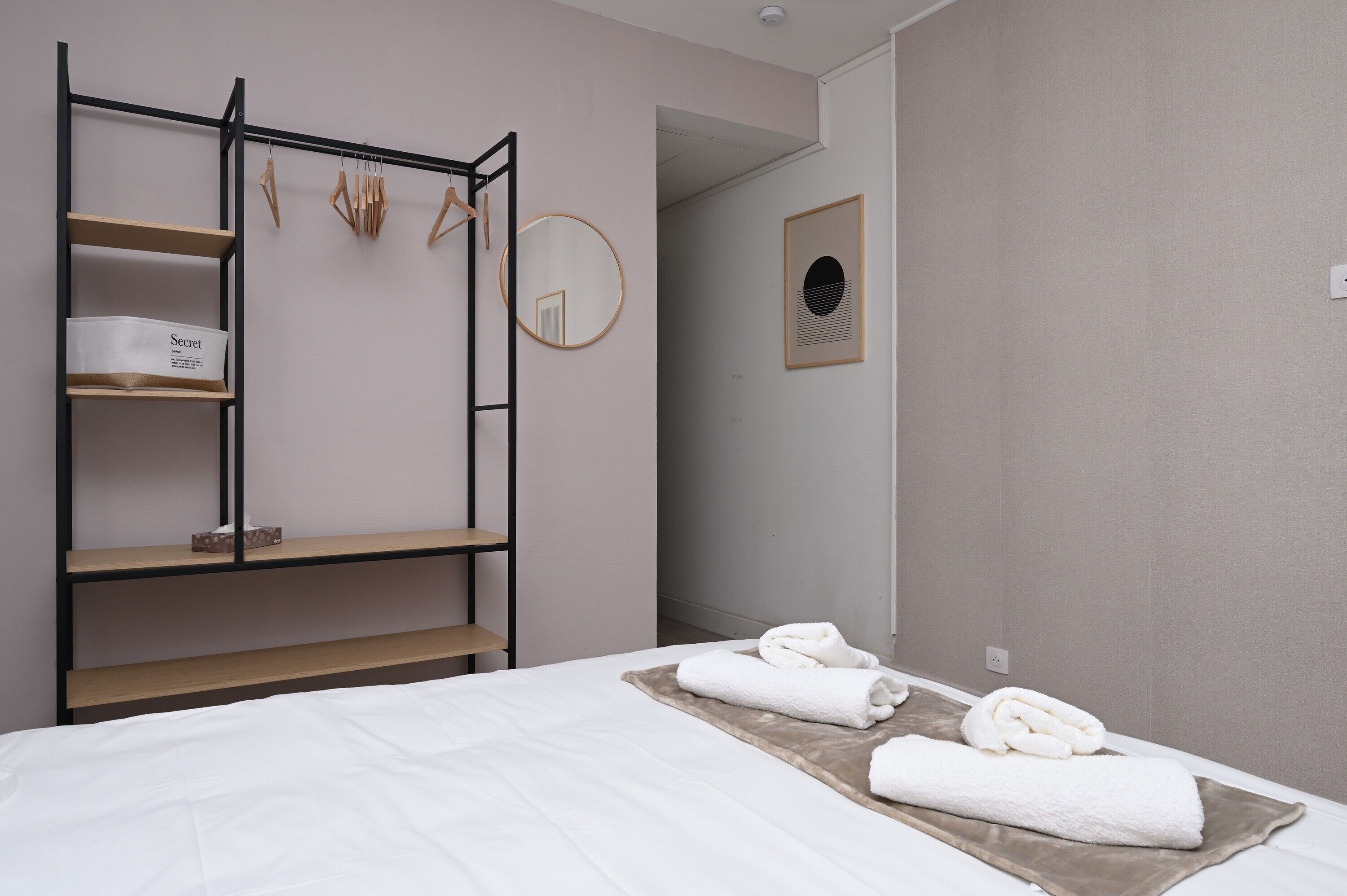 Une chambre avec un lit superposé, une table de chevet, un miroir et des serviettes soigneusement pliées.