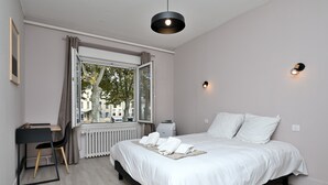A bedroom with a bed, a desk, a chair, a radiator, a window with curtains, and a pendant light. - Room 'Double Room' with Shared Terrace, Wi-Fi and Air Conditioning (Salies-du-Salat)
