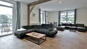 Ein modernes Wohnzimmer mit einer Eckcouch, einem Couchtisch und einem Essbereich mit Stühlen.