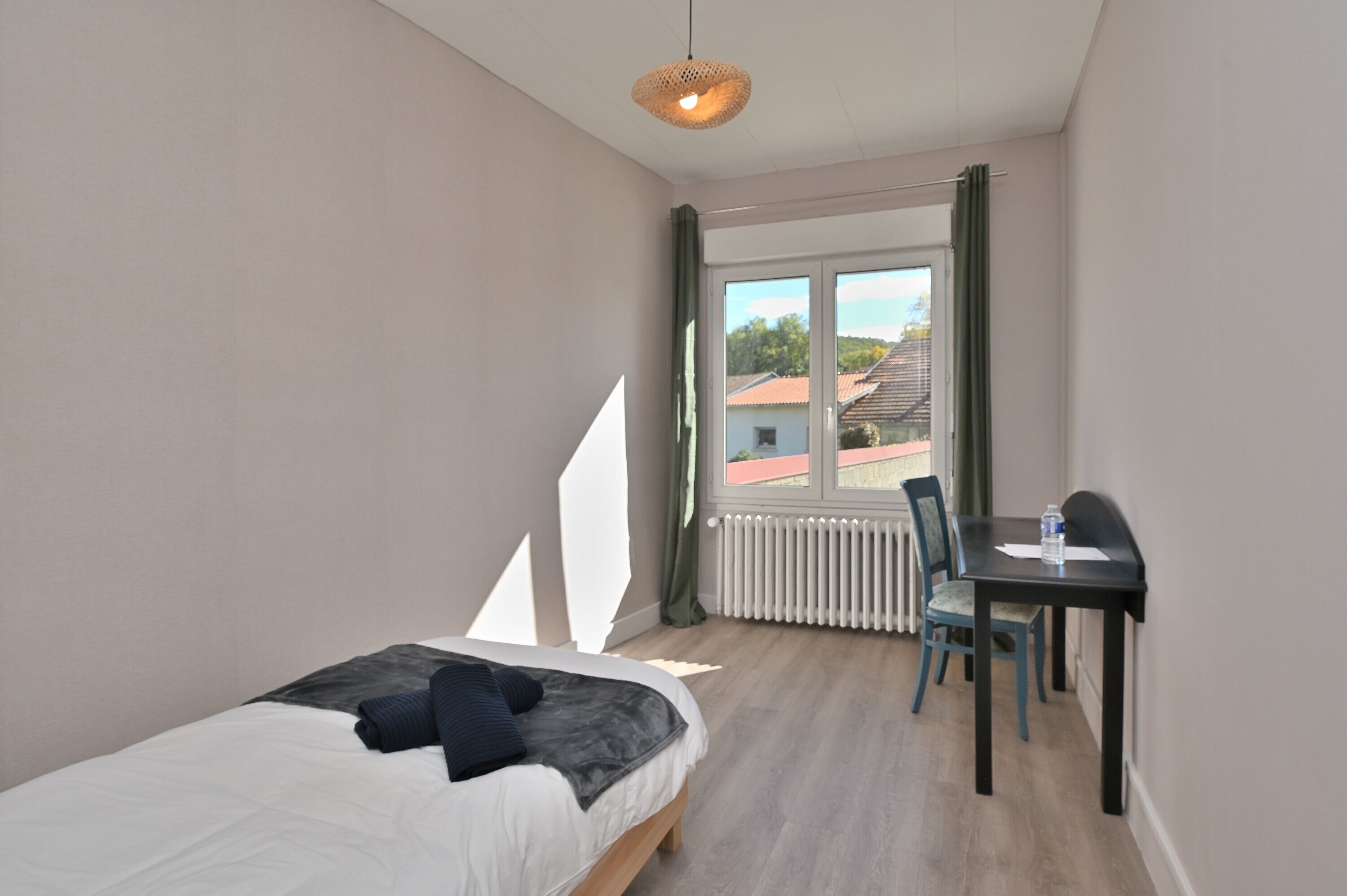 Een slaapkamer met een bed, een bureau en een radiator.