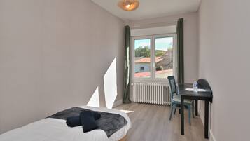 Een slaapkamer met een bed, een bureau en een radiator.