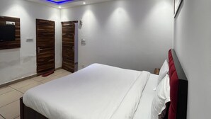 A modern bedroom with a bed, a ceiling fan, recessed lighting, and a TV mounted on the wall. - Roomshala J S Garden (Noida)