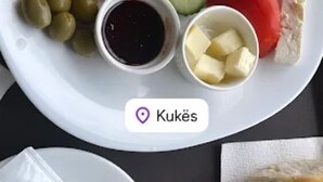 Prato com linguiça, legumes e acompanhamentos, além de uma xícara de café e um copo de suco de laranja.