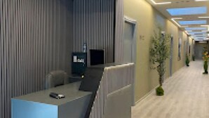 Uma área de recepção moderna com balcão, assentos e uma televisão de tela plana.