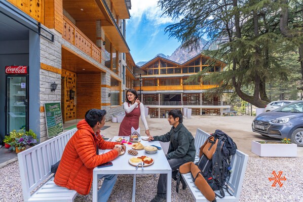 A group of people dining outdoors at a restaurant with a mountain view.
