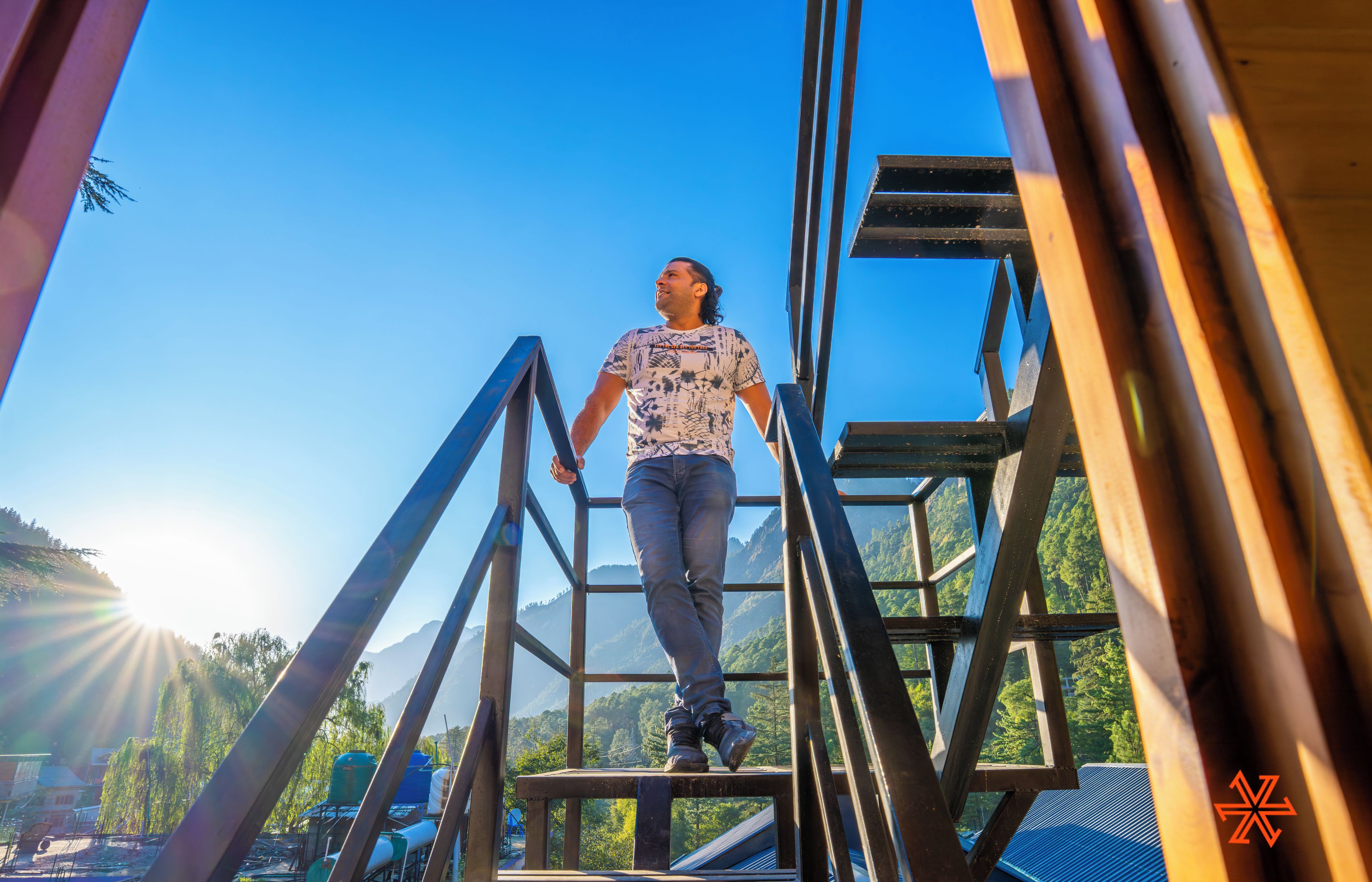 Eine Person geht eine Metalltreppe hinauf, im Hintergrund eine gebirgige Landschaft.