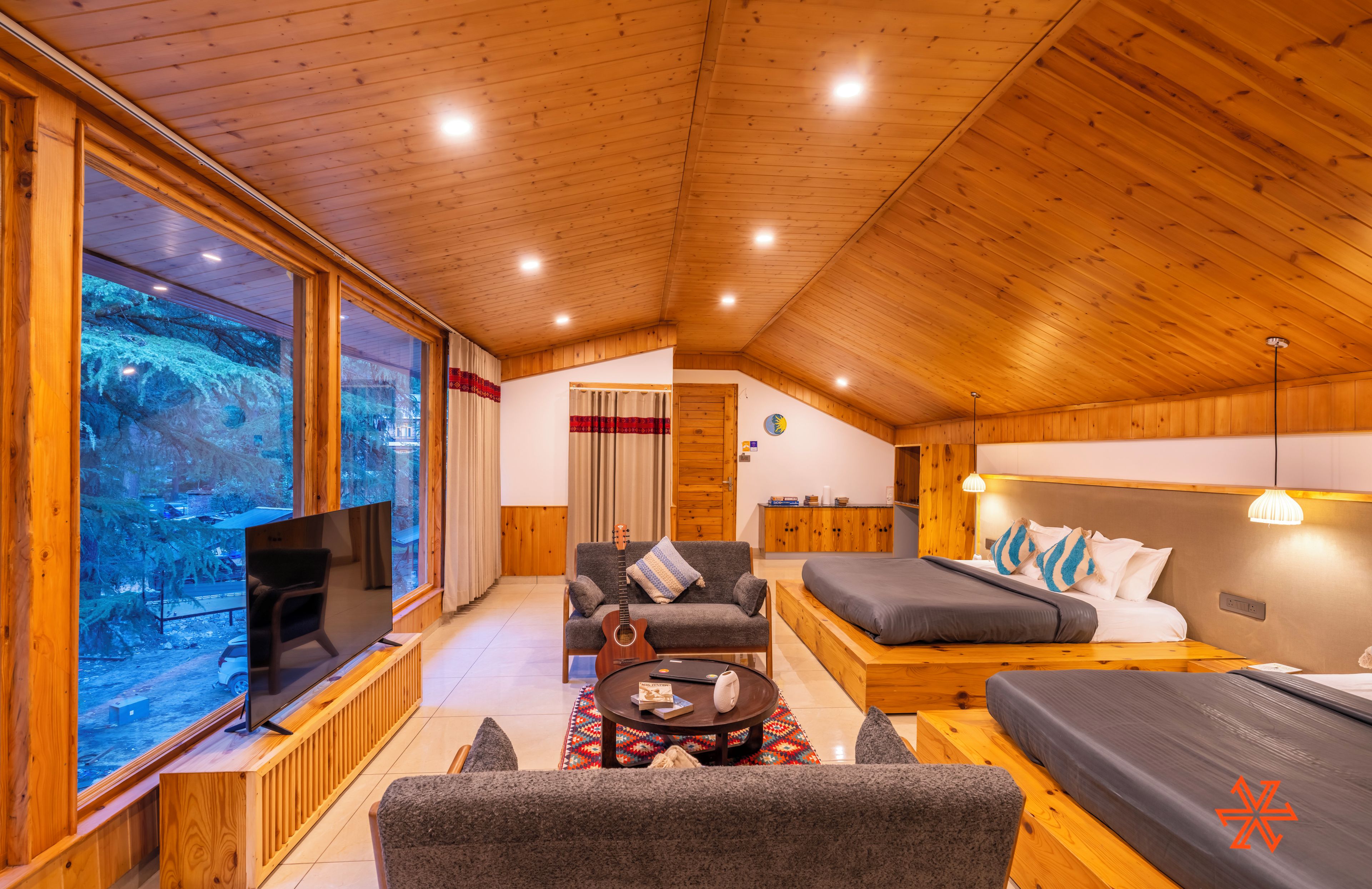 A cozy, wooden-floored room with a TV, sofa, and bed.