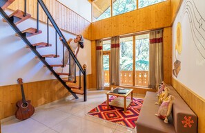 A wooden interior with a staircase, a sofa, a table, and a guitar. - Zostel Kasol (Main Market) (Kasol)