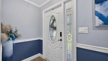 A hallway with a white door, a stained glass window, and a wall-mounted light switch.