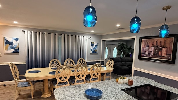 Een moderne keuken met granieten aanrecht, een ingebouwde kookplaat en een eethoek met een houten tafel en stoelen.