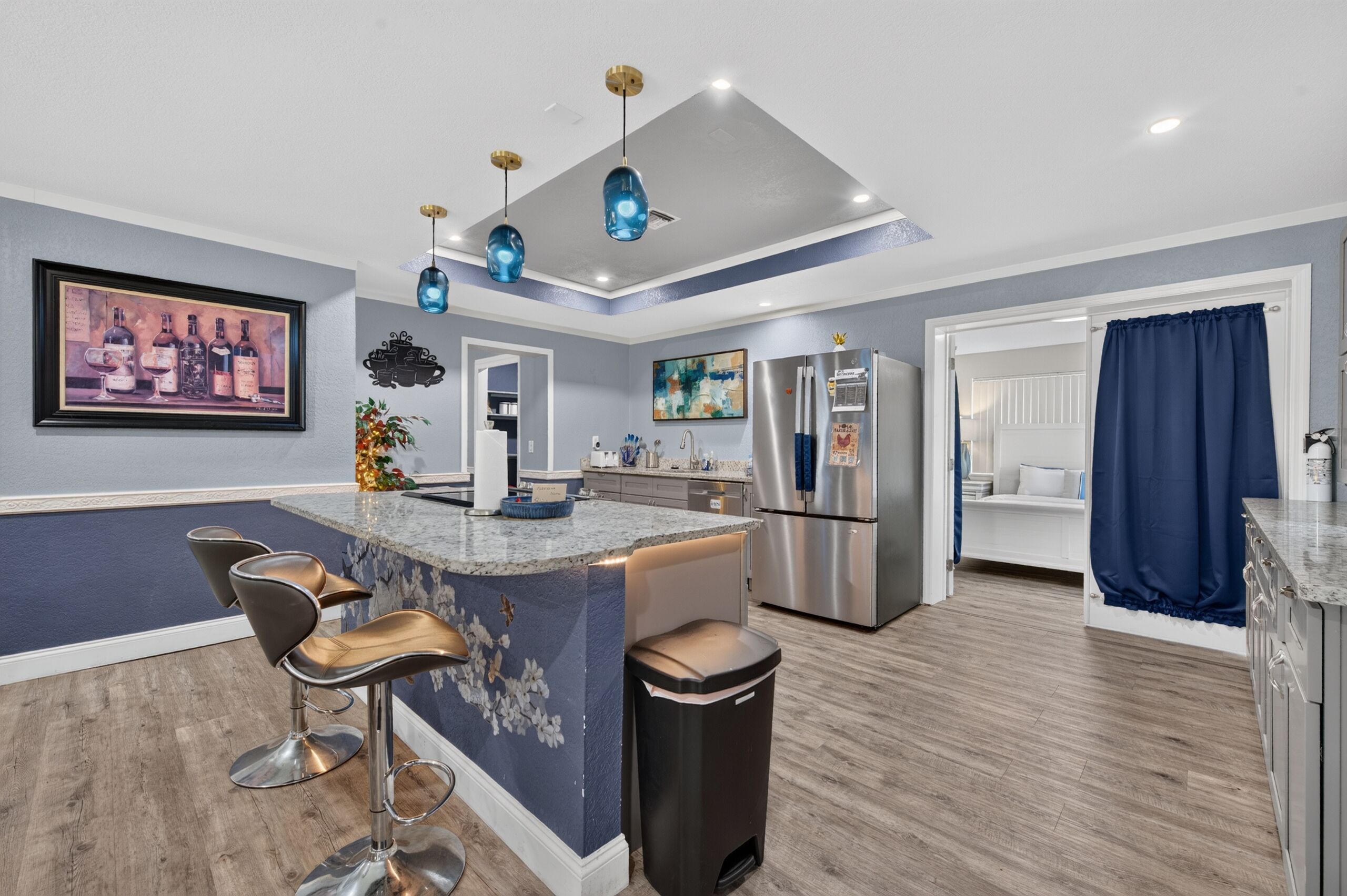 Una cocina moderna con una isla central, taburetes de bar, un refrigerador y un comedor.