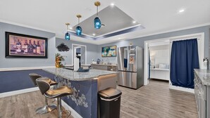 Een moderne keuken met een centraal eiland, barkrukken, een koelkast en een eethoek.