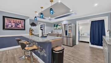 Una cocina moderna con una isla central, taburetes de bar, un refrigerador y un comedor.