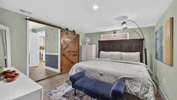 Een slaapkamer met een bed, een bureau, een stoel, een kledingkast en een schuifdeur.