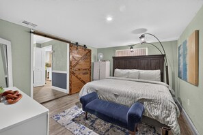 Un dormitorio con una cama, un escritorio, una silla, un armario y una puerta corredera.
