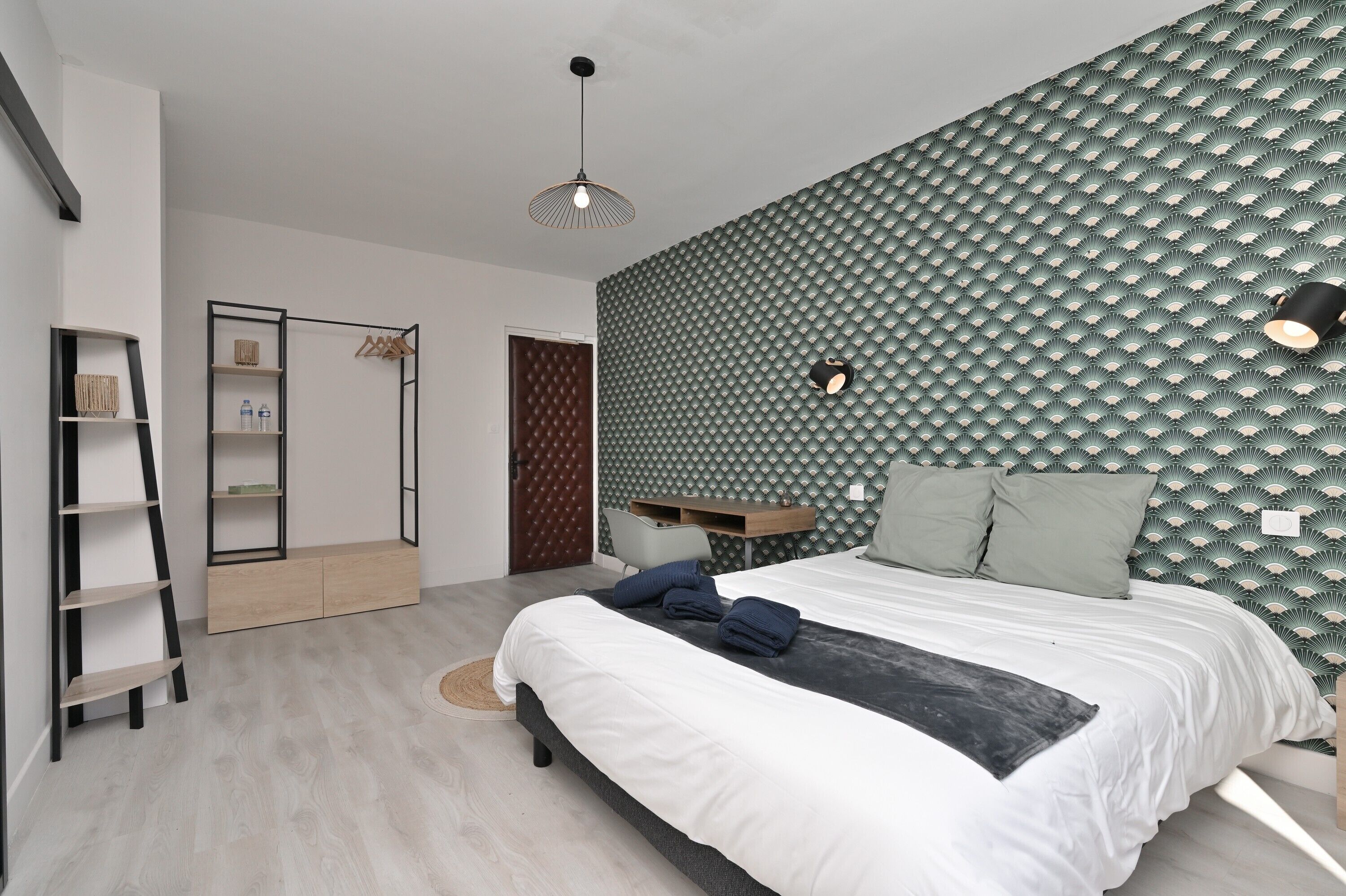 Une chambre moderne comprenant un lit, un bureau, une armoire et un luminaire suspendu.